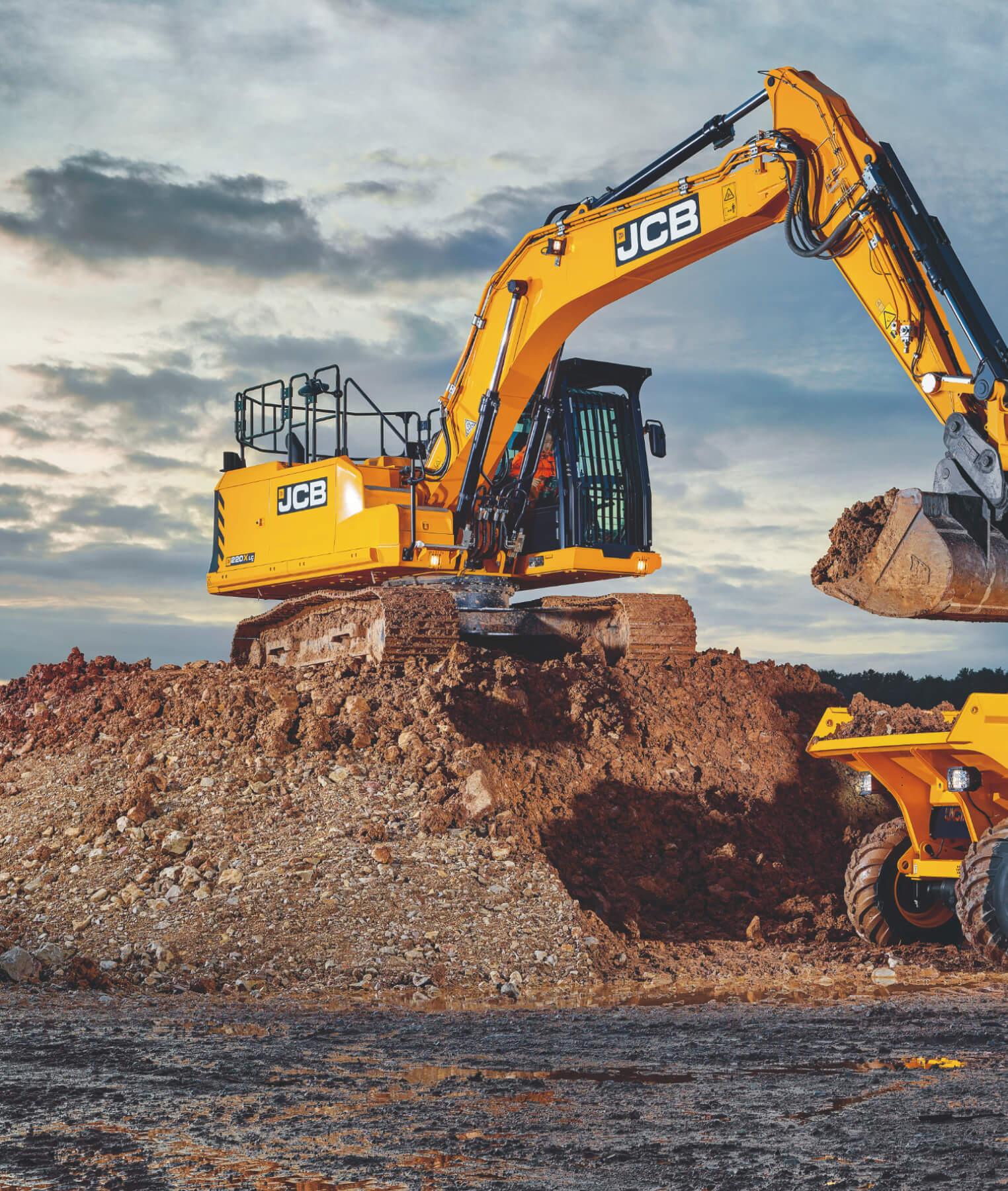 A yellow JCB excavator loads dirt into a dump truck at a construction site, with a cloudy sky in the background. The excavator is positioned on a mound of earth.