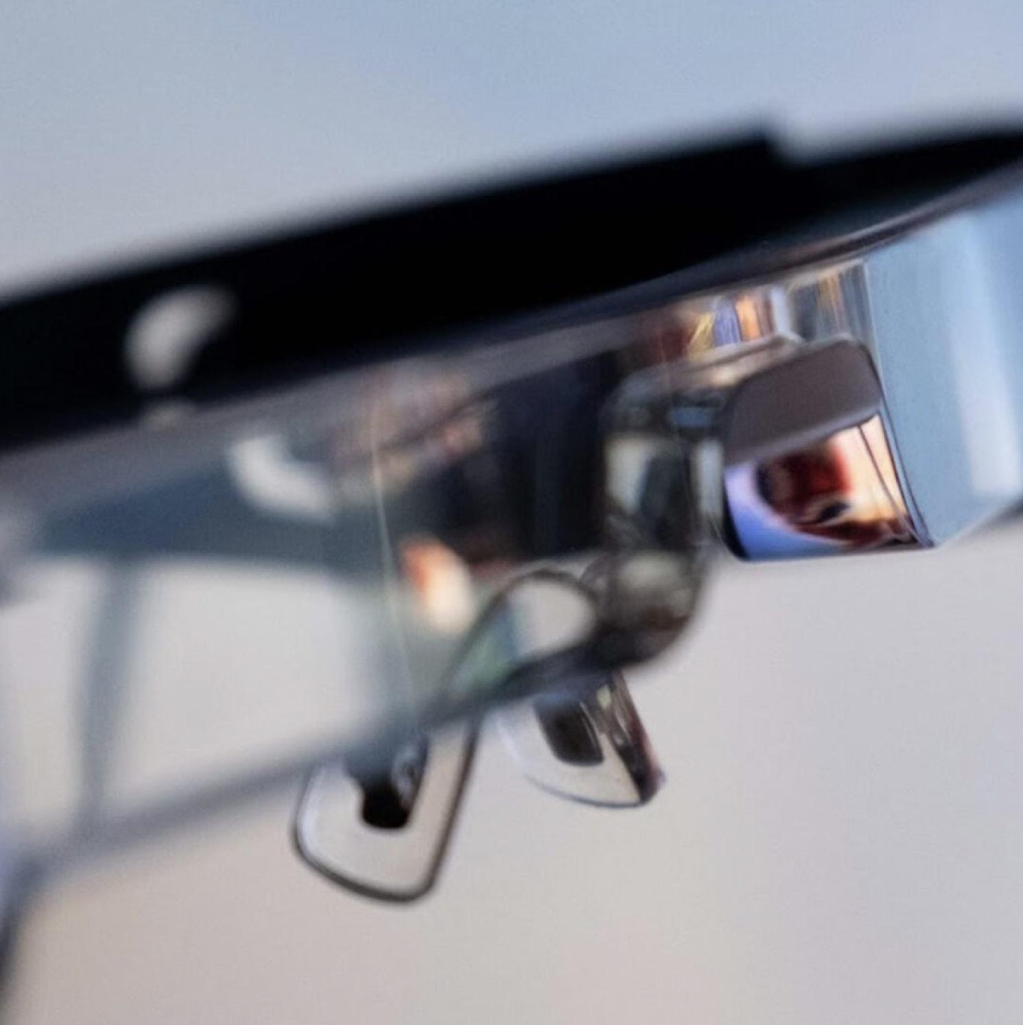 A close-up of smart glasses with a reflective lens, showing part of the frame and nose pads against a blurred background.