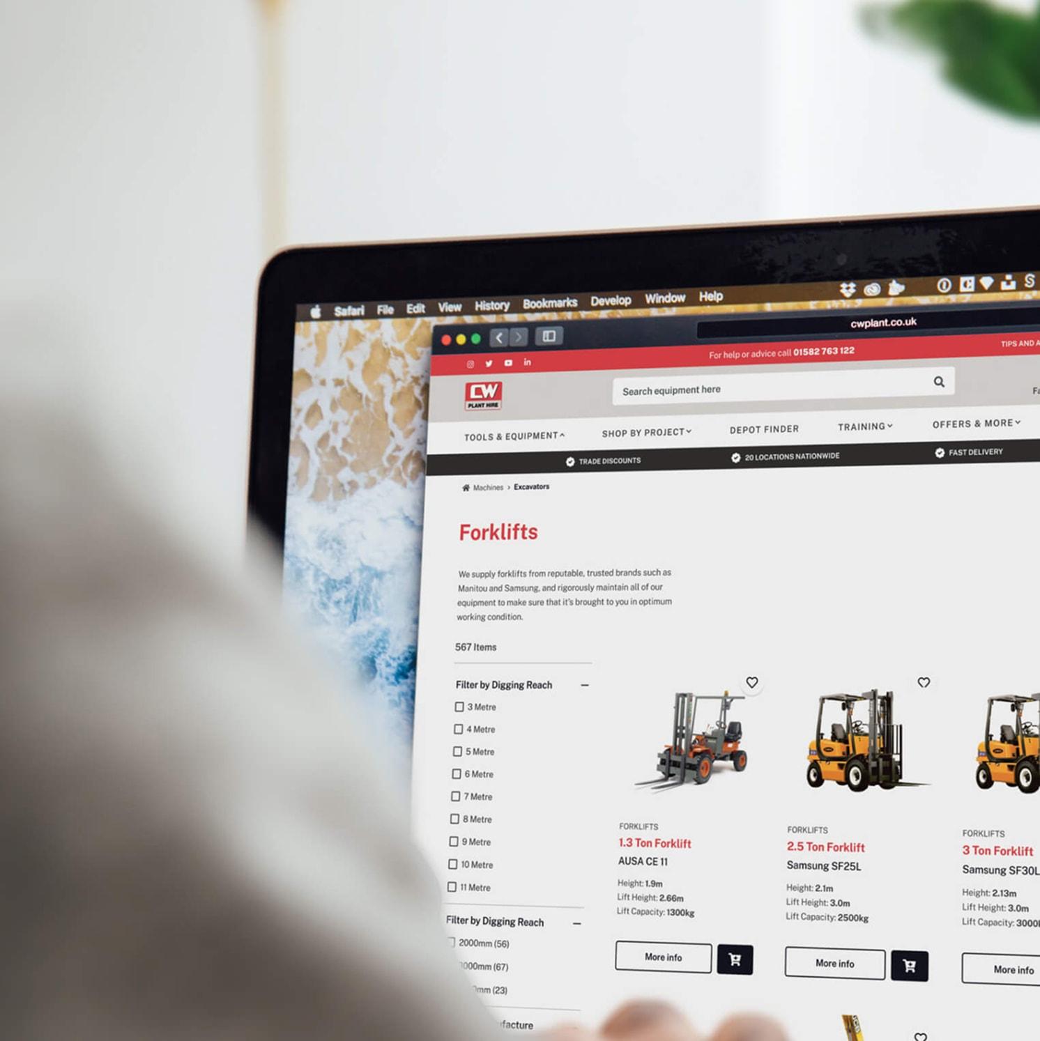 A person browses an online store for forklifts on a laptop, viewing images and details of different forklift models on the website.