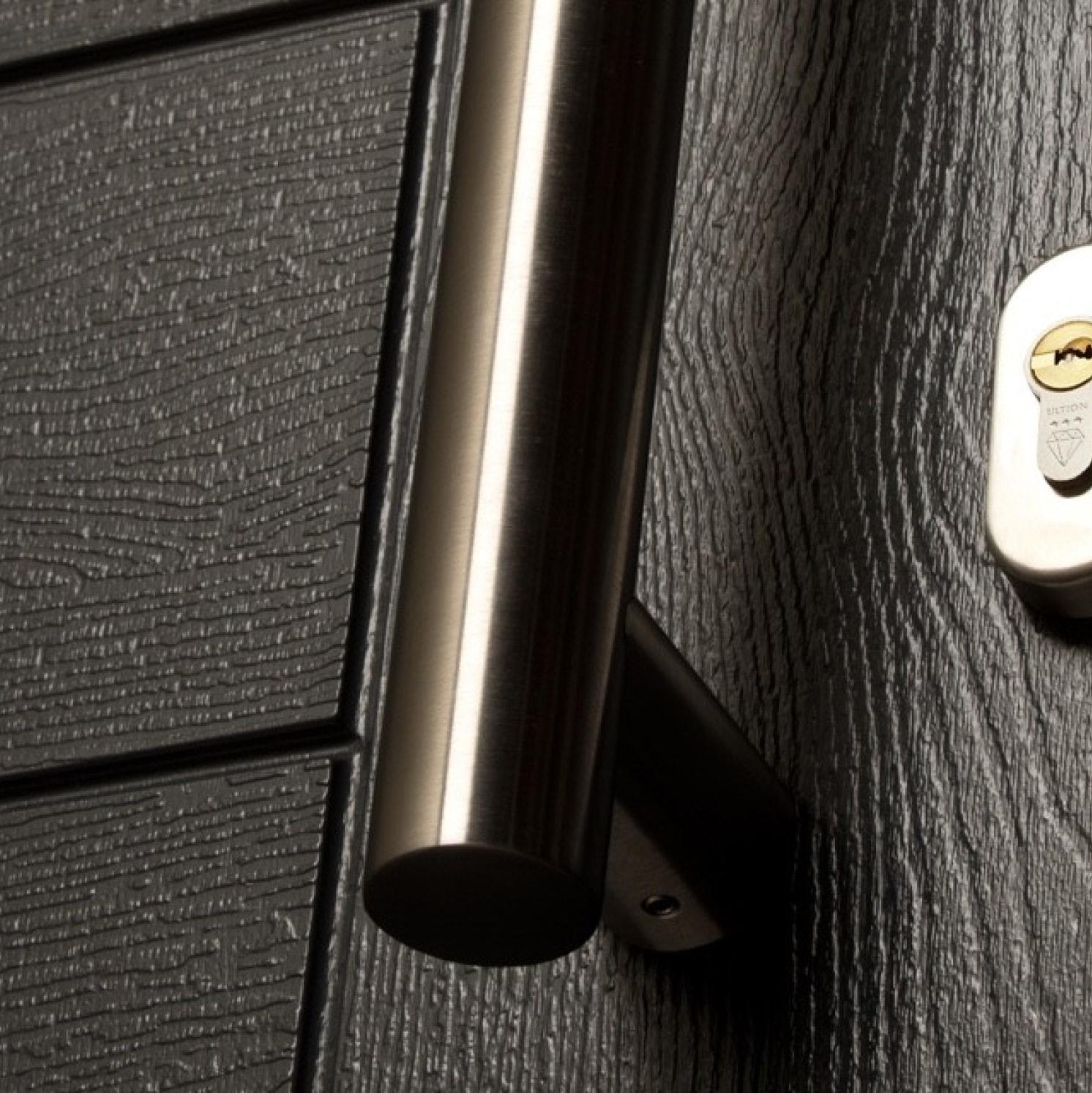 Close-up of a textured black door with a stainless steel vertical handle and a silver keyhole lock on the right side.